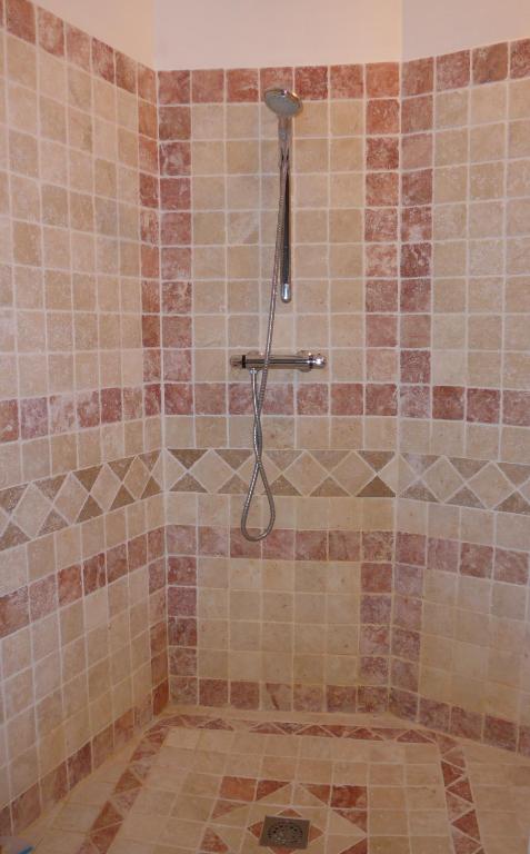 a shower in a bathroom with a tile floor at La Colline Bleue in Banne