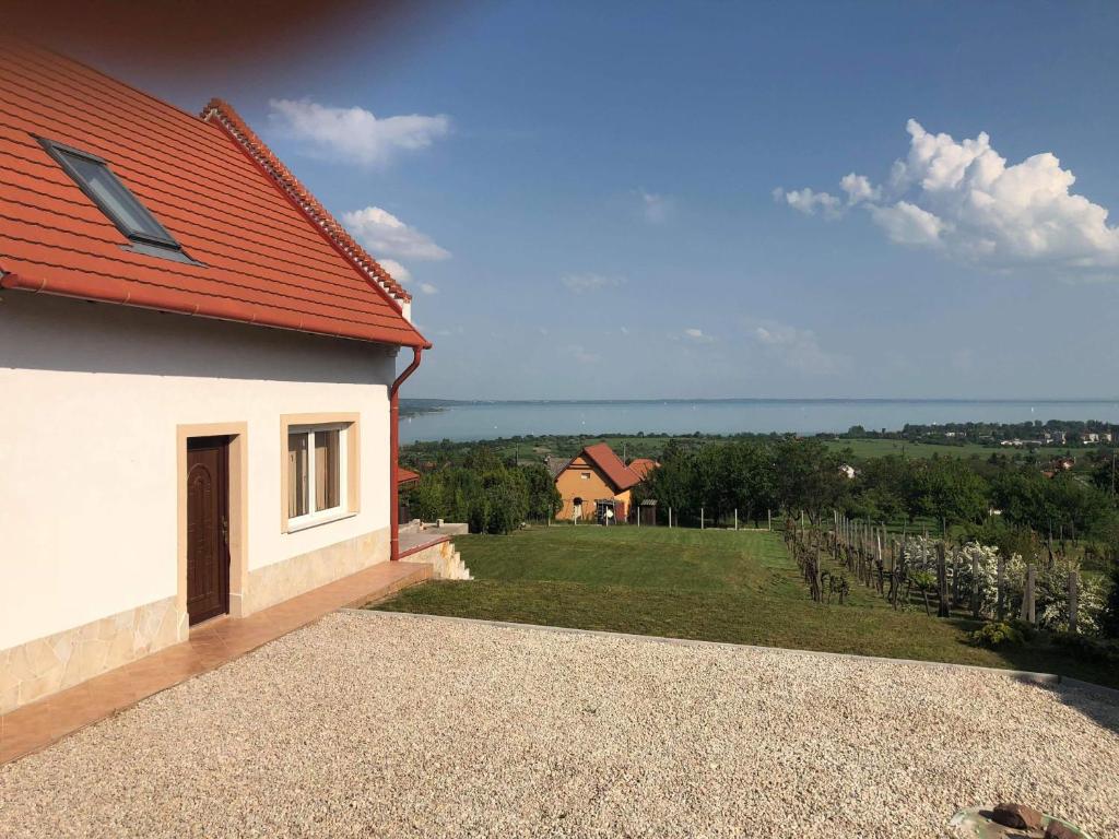 a white house with a red roof and a field at Mesgye Villa in Balatonalmádi