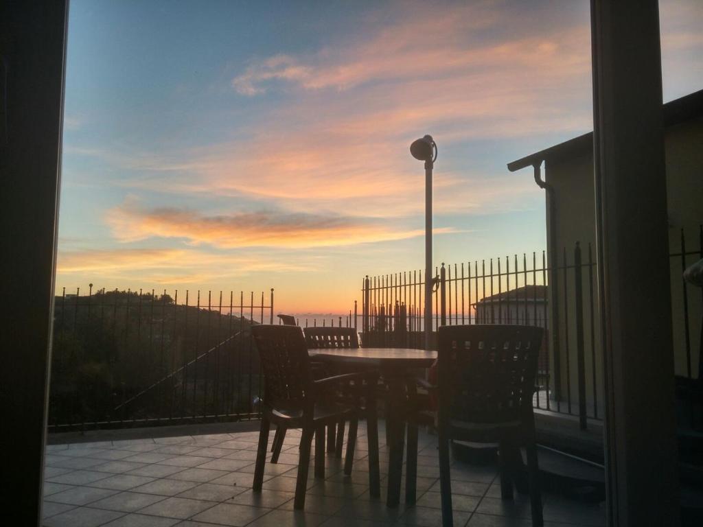 a table and chairs on a balcony with a sunset at Barbara's House - Liguria in Santo Stefano al Mare