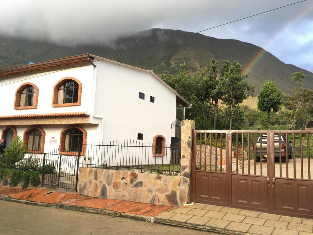 a white house with a fence and a rainbow at Hotel Casa Medina in San Mateo