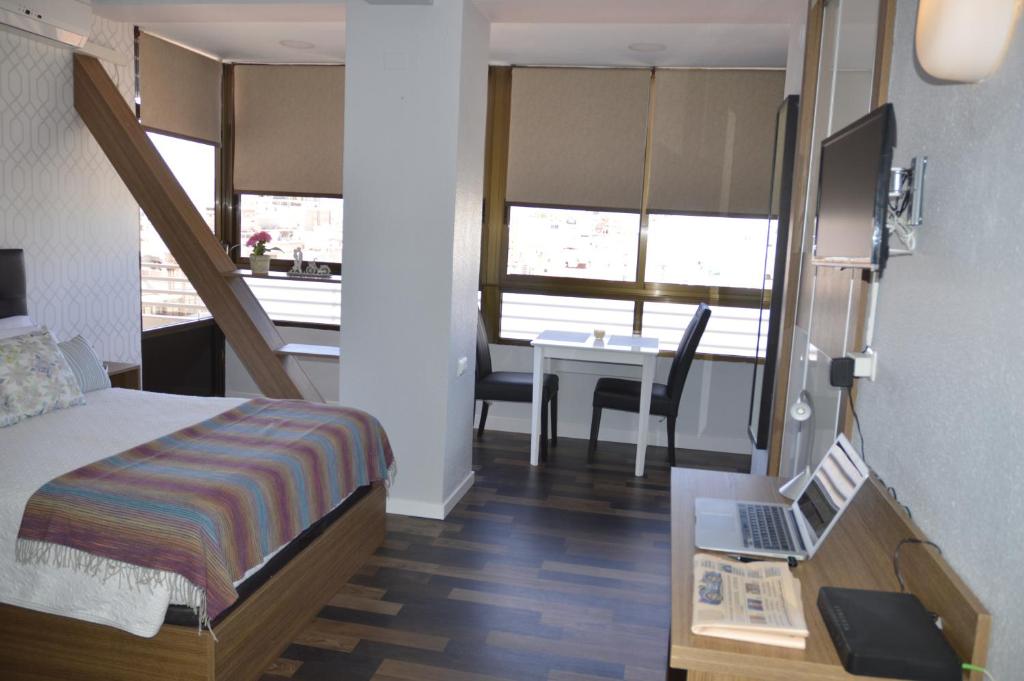 a bedroom with a bed and a desk with a laptop at Lukentum Suites in Alicante
