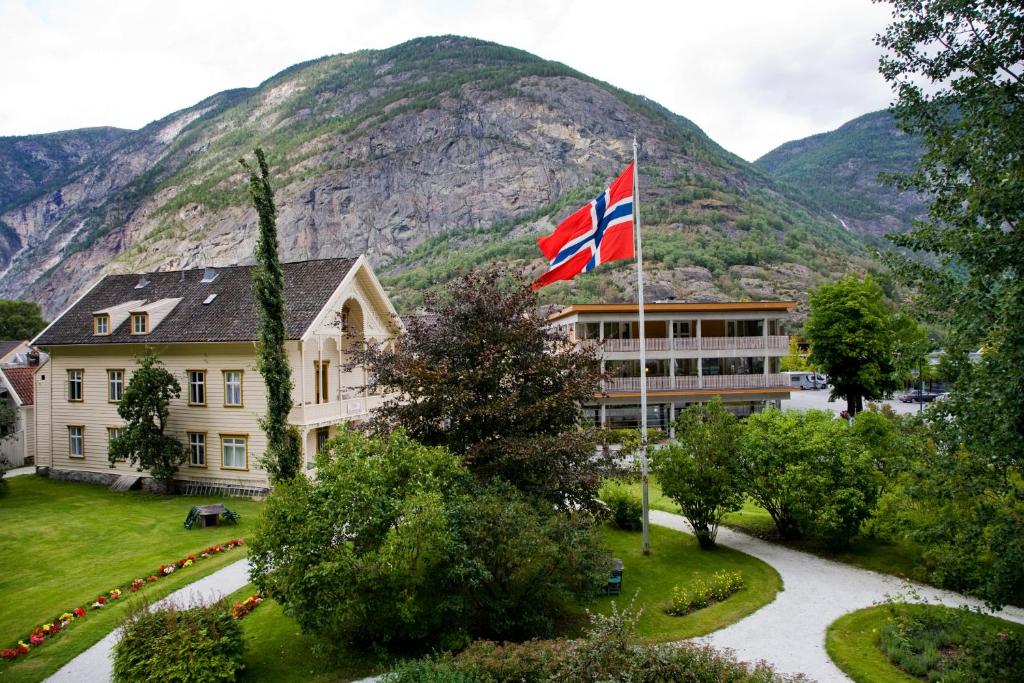 a building with a british flag in front of a mountain at Lindstrøm Hotel in Lærdalsøyri