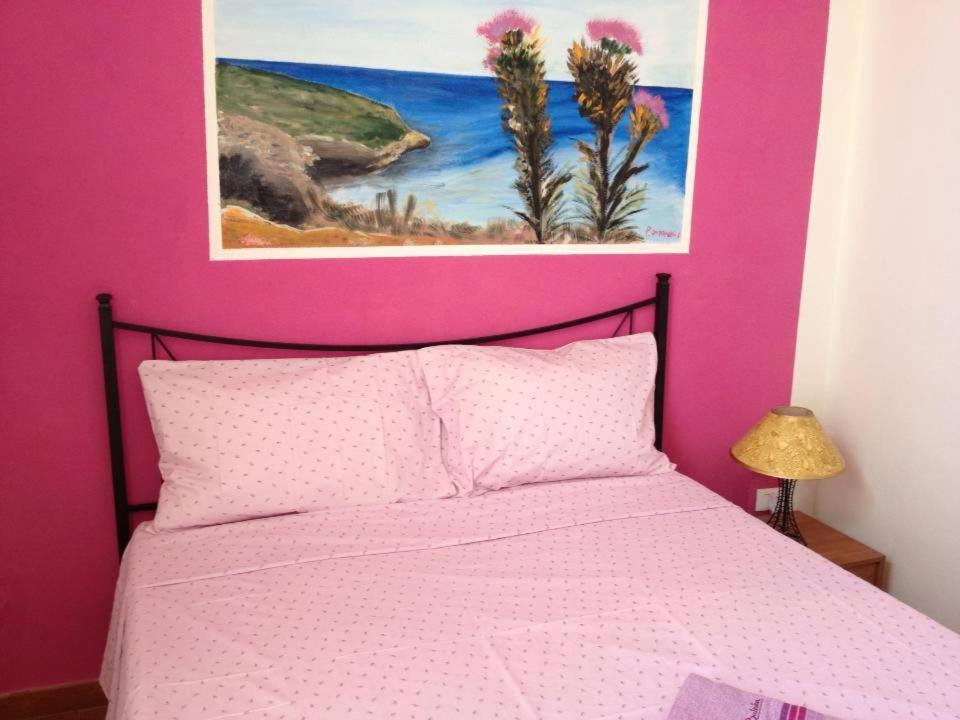 a pink bedroom with a bed with a pink wall at Lampedusa Vacanza in Lampedusa