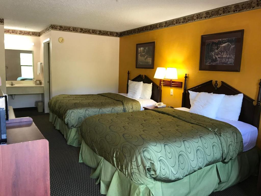 a hotel room with two beds and a desk at Clairmont Inn & Suites - Warren in Warren