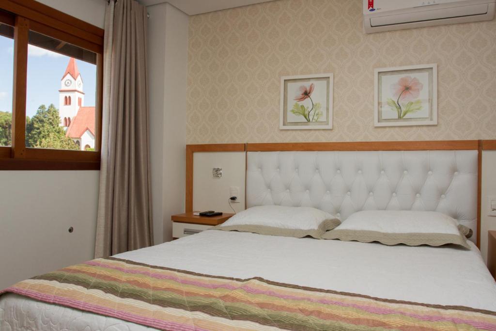 a bedroom with a white bed and a window at Ótima Localização e Vista da Cidade in Gramado