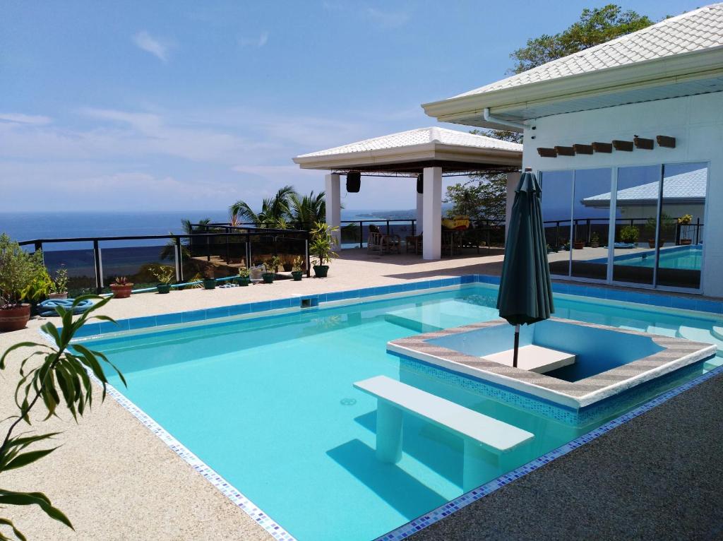 einen Pool mit Sonnenschirm neben einem Haus in der Unterkunft Seaview Mansion Apartment 1 in Dalaguete