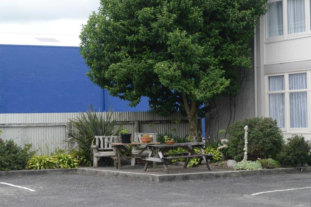 a picnic table and a tree next to a building at Alexander Motel in Taumarunui