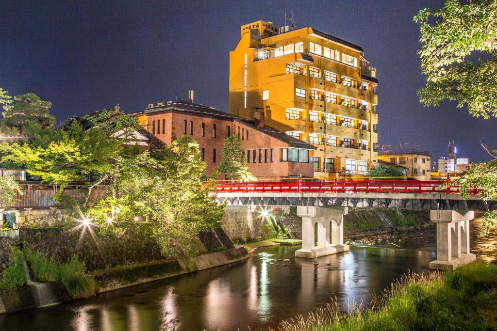 un train rouge traversant un pont sur une rivière dans l'établissement Honjin Hiranoya Annex, à Takayama