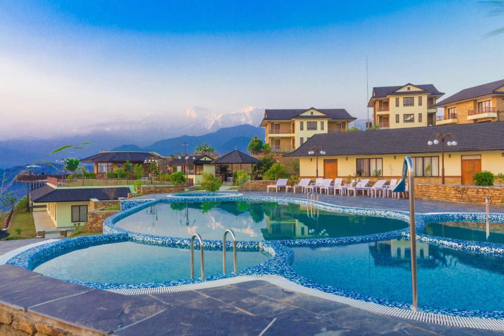 a swimming pool in a resort with mountains in the background at Rupakot Resort in Pokhara