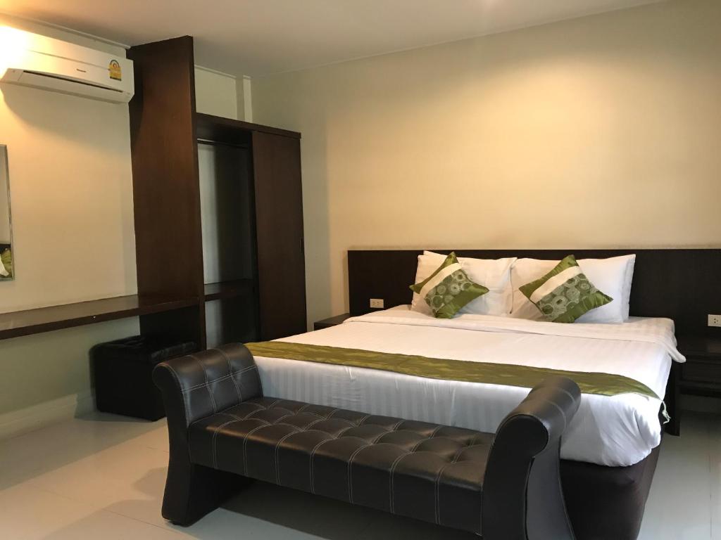 a bedroom with a large bed with a leather couch at Chiangrai Green Park Resort in Chiang Rai