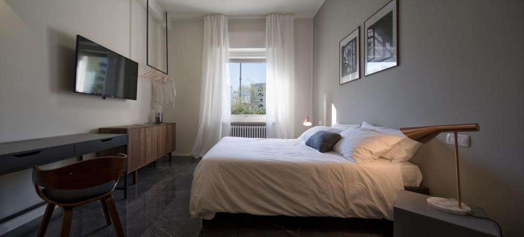 沃蓋拉的住宿－Suite Vogue Stazione，一间卧室配有一张床、一张书桌和一个窗户。