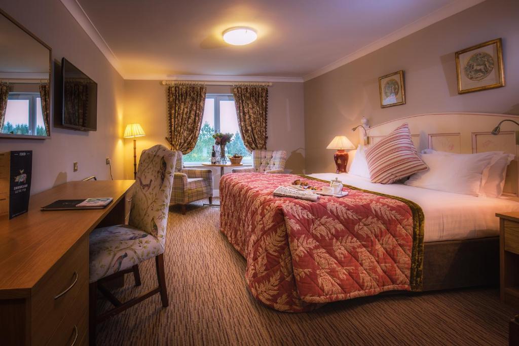 a hotel room with a large bed and a desk and a desk at The Inn at Dromoland in Newmarket on Fergus