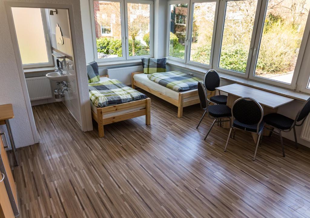 Zimmer mit einem Tisch, Stühlen und Fenstern in der Unterkunft BoardingHouse Quickborn in Quickborn