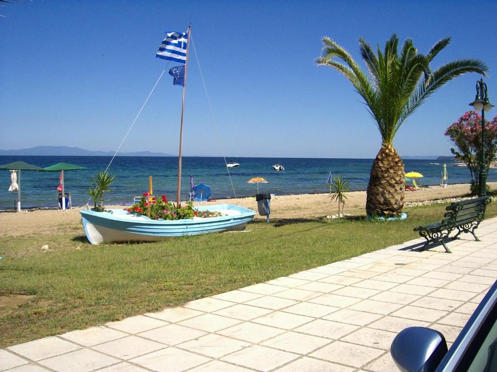 a boat on the beach with a flag and a palm tree at Holiday Home by the Sea in Nea Potidaea