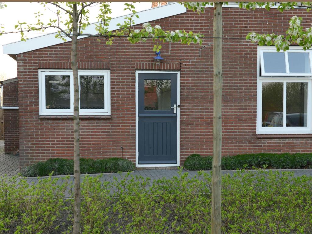 una casa de ladrillo rojo con una puerta negra en Het Wilgenhoekske en Serooskerke