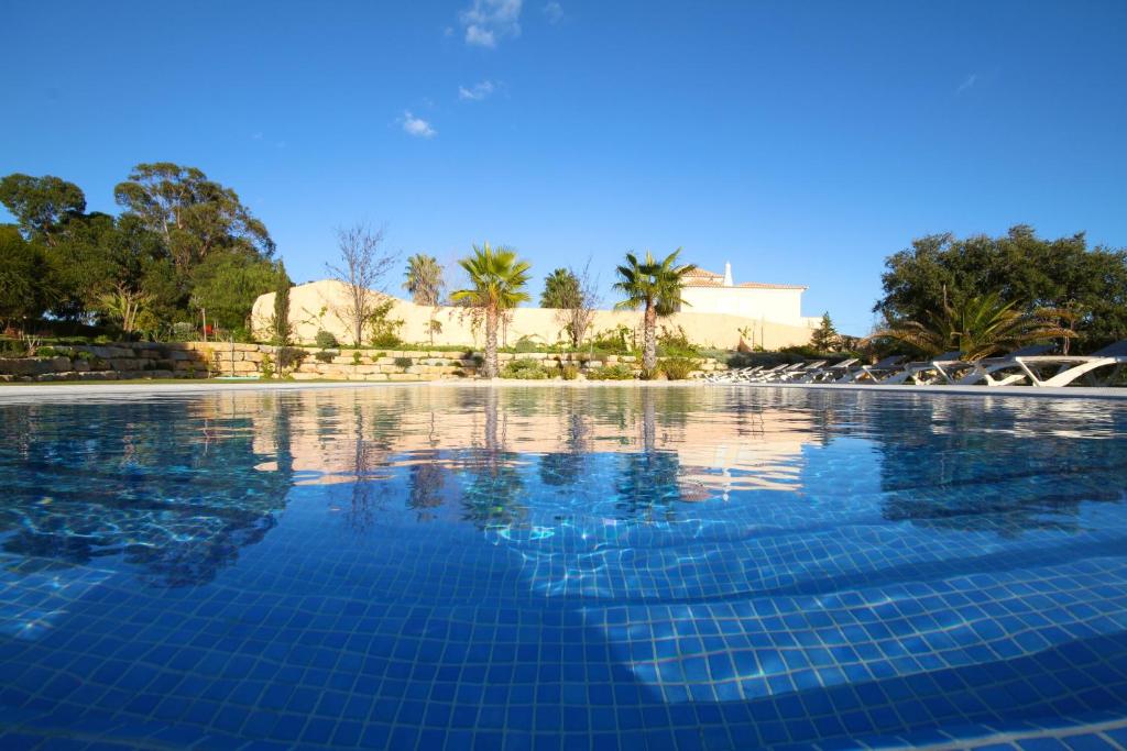 una piscina con agua azul y palmeras en Pinheiros da Balaia Villas, en Albufeira