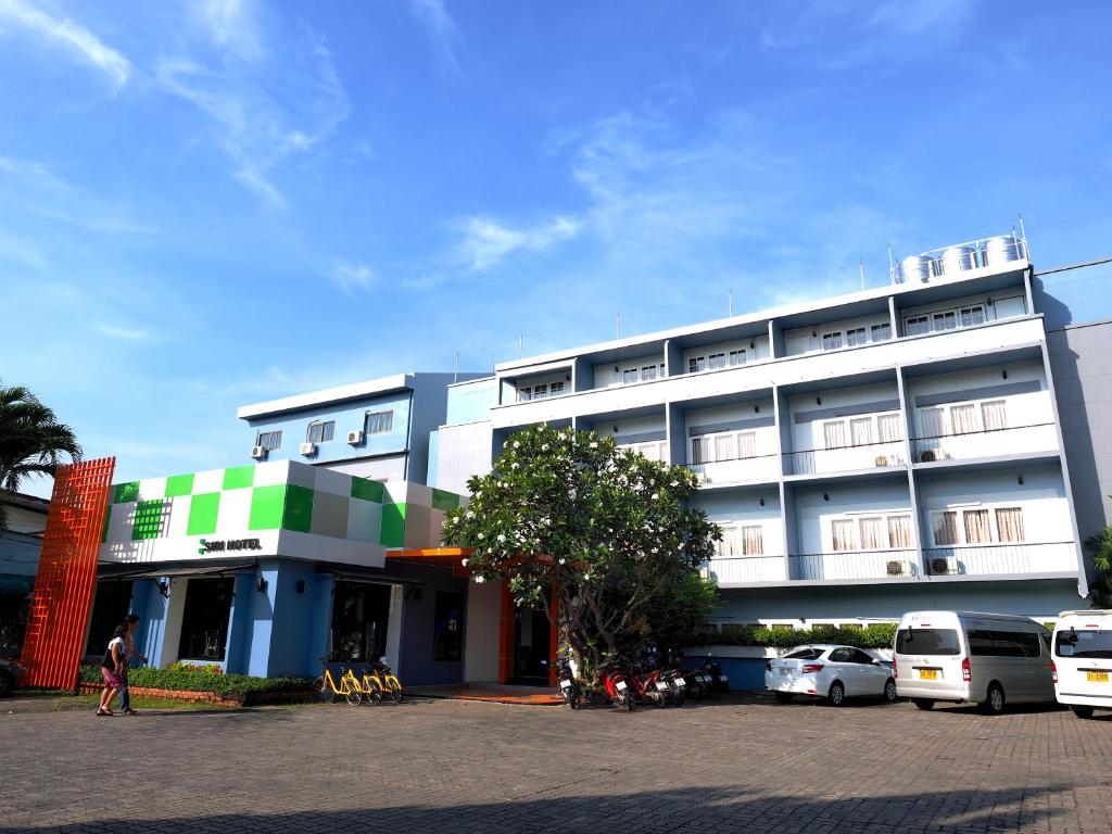 un grand bâtiment avec des voitures garées devant lui dans l'établissement Siri Hotel Phuket, à Phuket