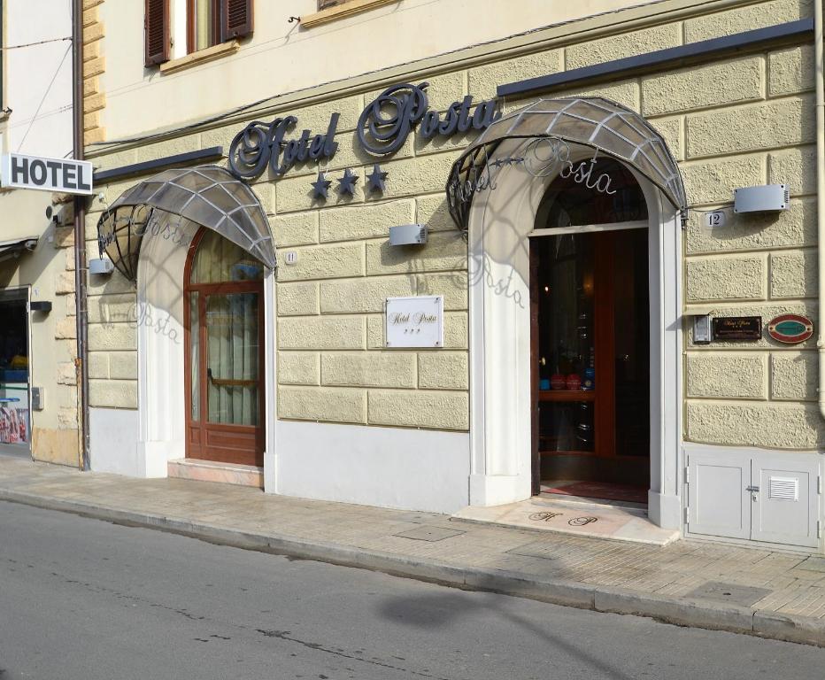 uma loja com duas portas arqueadas num edifício em Hotel Posta em Cecina