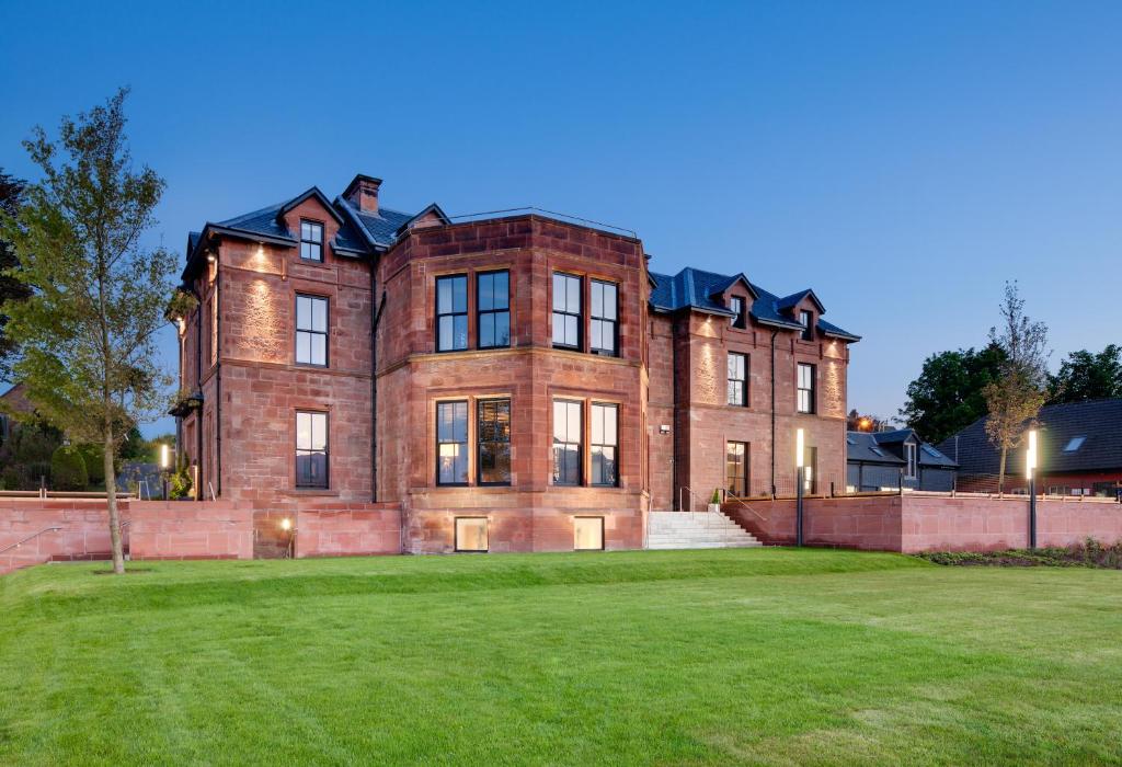a large brick building with a large grass field at The Douglas Hotel in Brodick