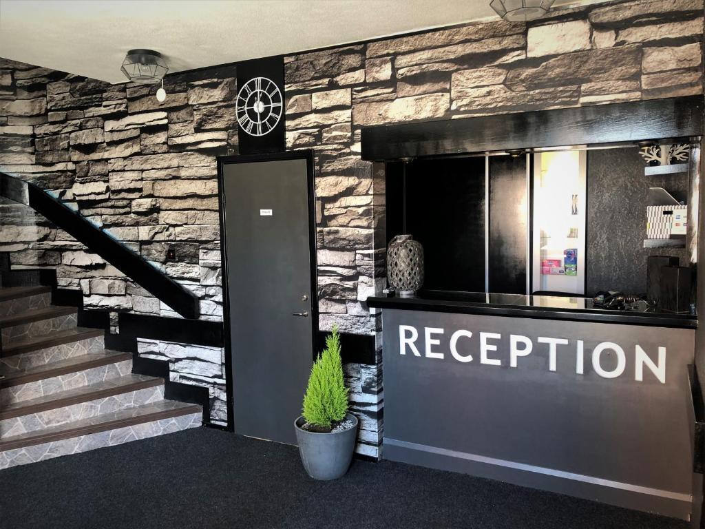 a lobby with a stone wall and a reception door at Dentas Hotell Raivi in Hoting