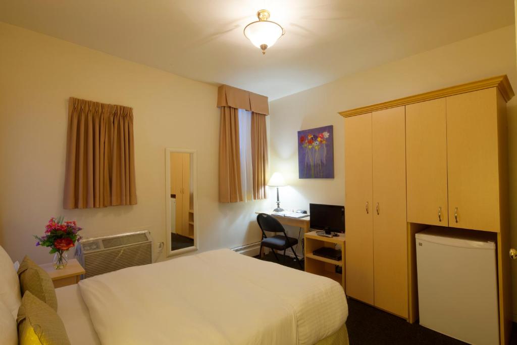 a hotel room with a bed and a desk at Victoria's Mansion Guest House in Toronto