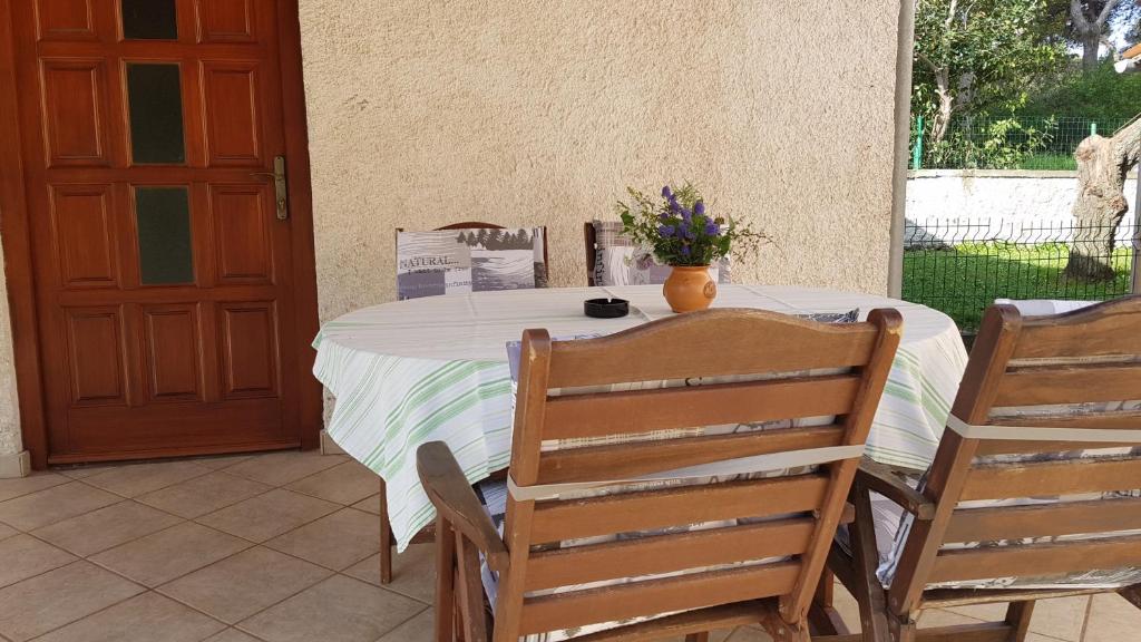 a table with two chairs and a vase of flowers on it at Apartment Ecio in Banjole