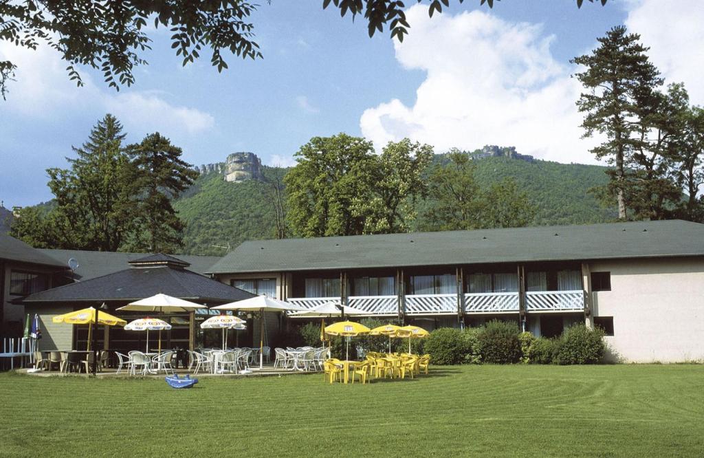 un bâtiment avec des tables et des parasols devant lui dans l'établissement Domaine Du Roc Nantais, à Nant