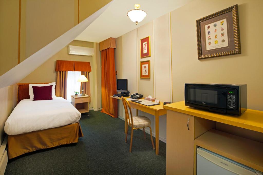 a hotel room with a bed and a desk with a tv at Victoria's Mansion Guest House in Toronto
