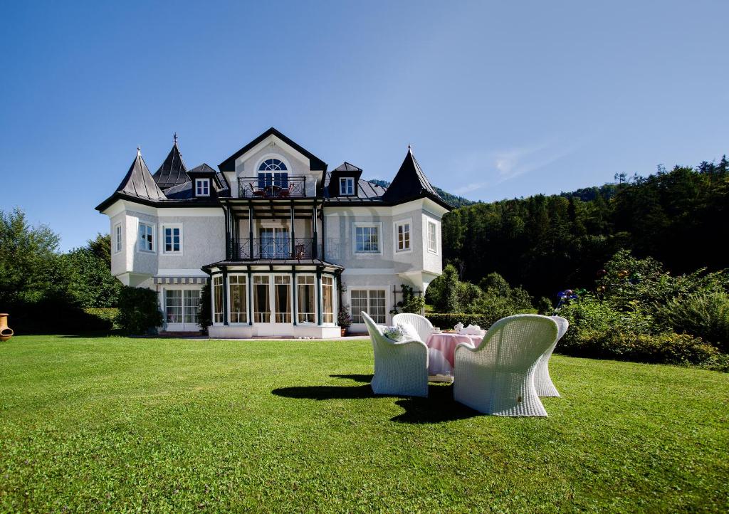 a house with a table and chairs in the grass at Hotel Seewinkel in Fuschl am See