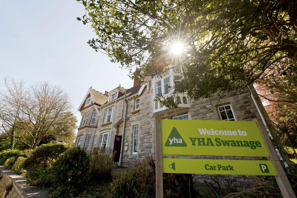 una señal frente a una casa con un edificio en YHA Swanage en Swanage