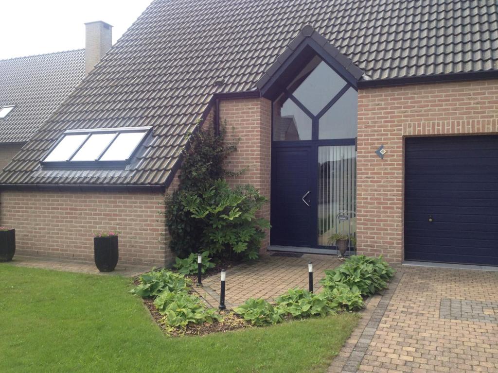 una casa in mattoni con una porta blu del garage di didi logement a Westerlo