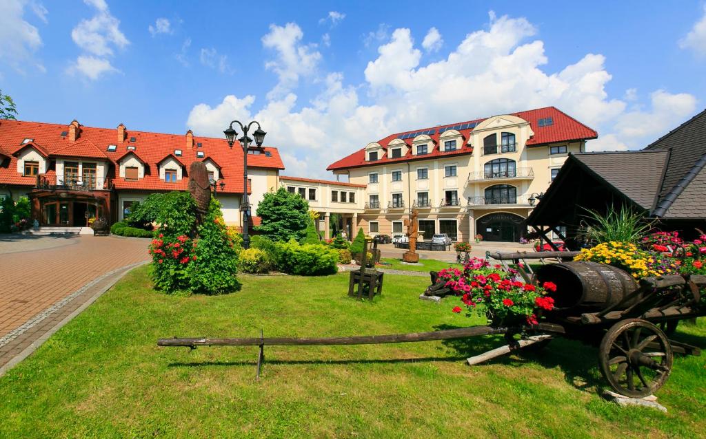 a garden with a horse drawn cart in front of a building at Hotel Galicja Superior Wellness & Spa in Oświęcim