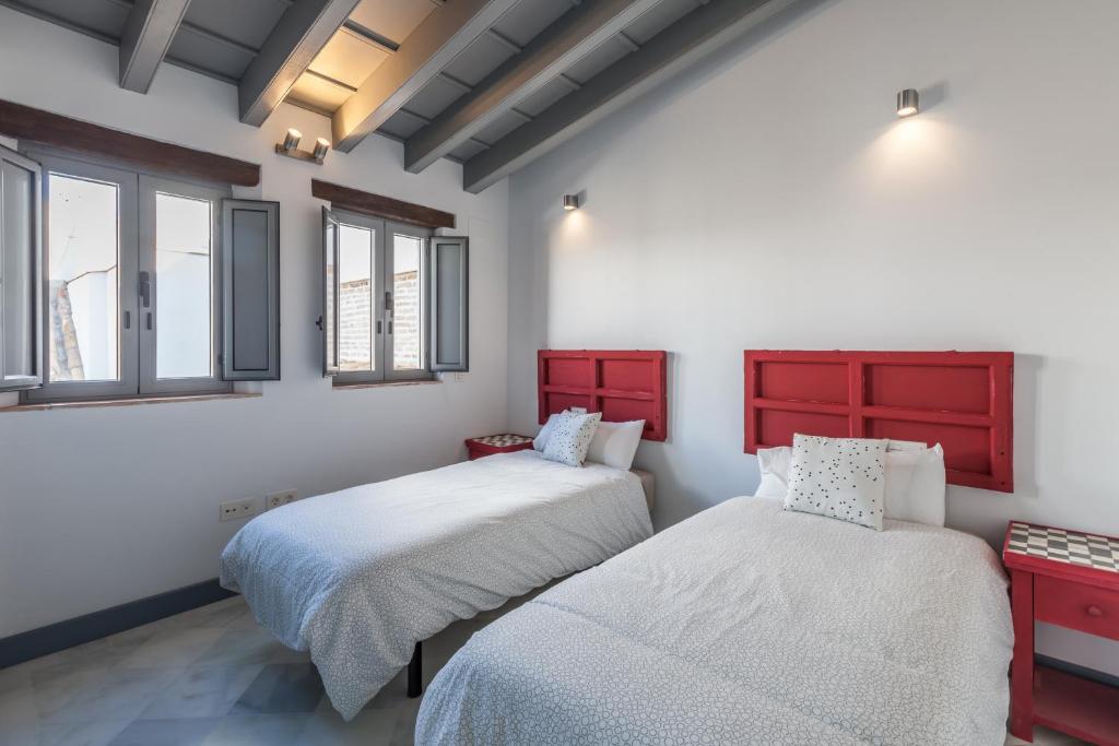 セビリアにあるCasas de Sevilla - Apartamentos Tintes12の赤いキャビネットと窓が備わるドミトリールームのベッド2台分です。