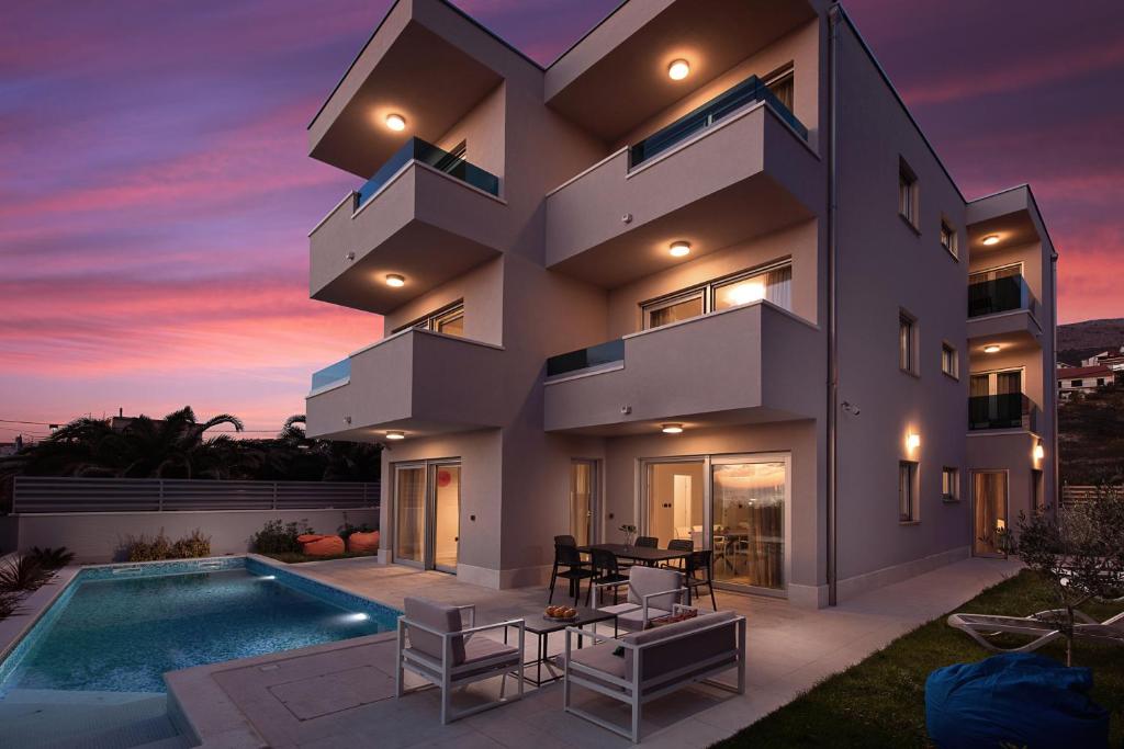 a modern house with a swimming pool at dusk at Luxury Villa Karla in Podstrana