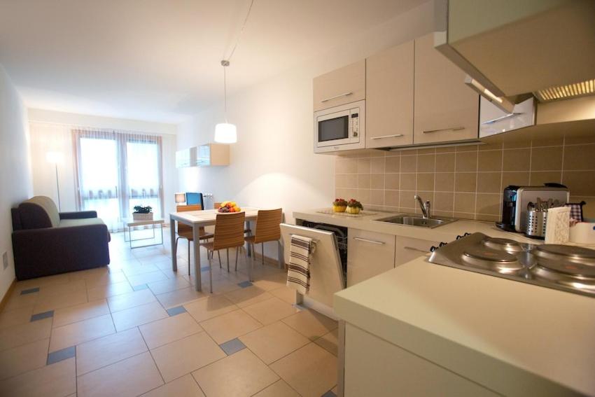 cocina y sala de estar con mesa y sillas en Lacroma Aparthotel, en Grado