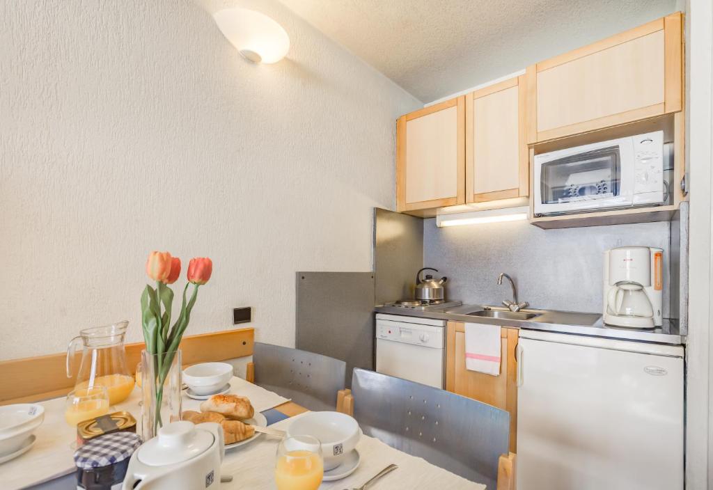 a kitchen with a table with orange tulips on it at Résidence Pierre & Vacances Inter-Résidences in Tignes