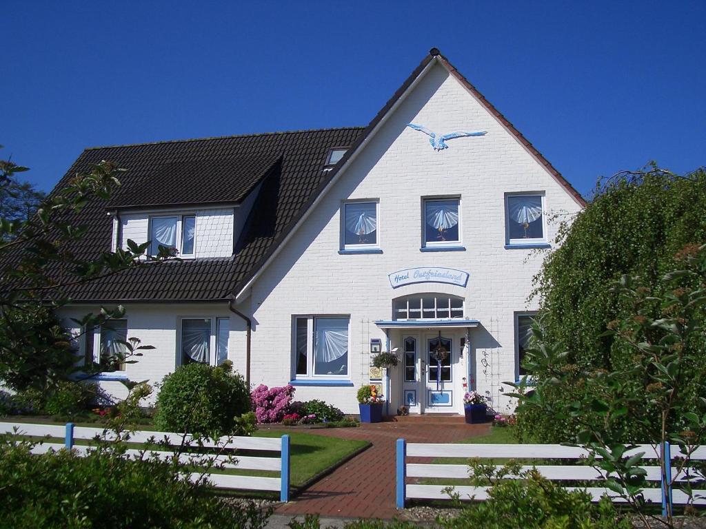 uma casa branca com um telhado preto em Hotel Ostfriesland garni em Norden