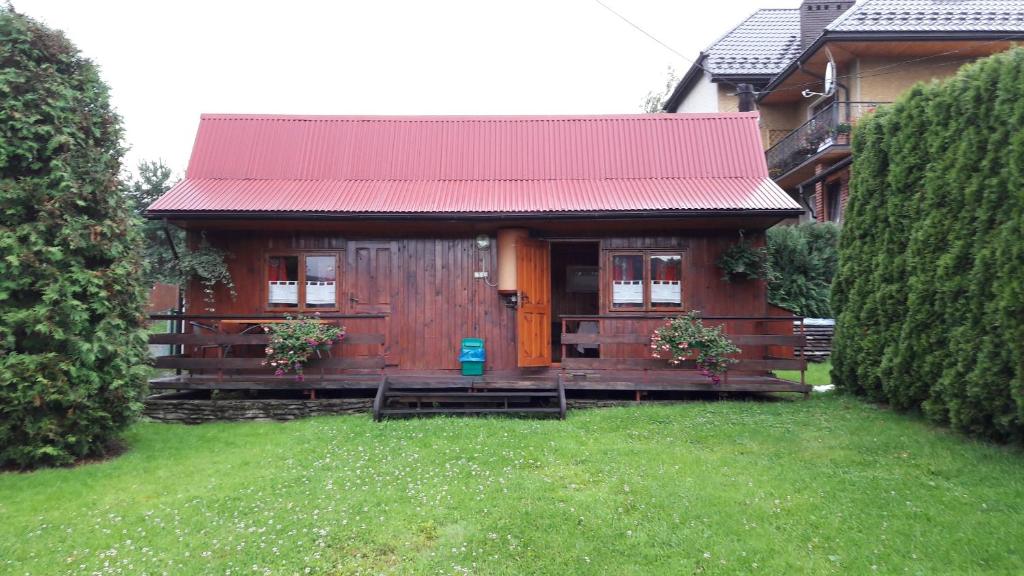 een klein houten huis met een rood dak bij Tanie Spanie in Wysowa-Zdrój