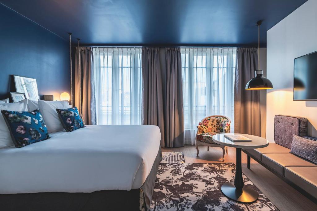 a hotel room with a large bed and a table at Le Belleval in Paris