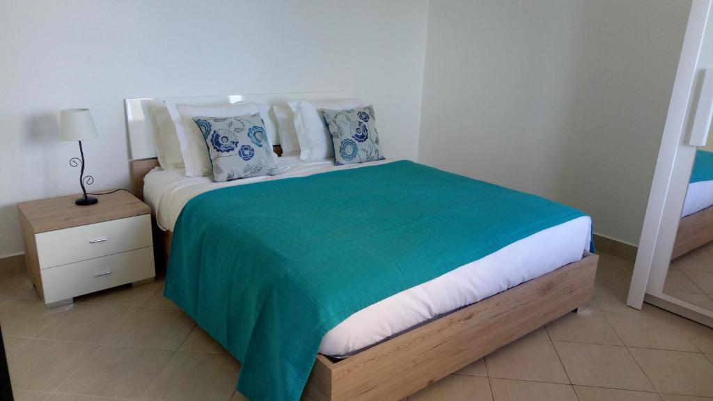 een slaapkamer met een bed met een groene deken en kussens bij Vivenda Cabral in Funchal