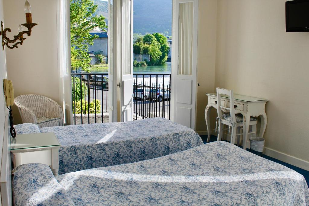 a room with two beds and a balcony with a view at Hôtel Sainte Marie in Lourdes