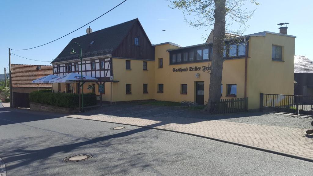 a yellow building with a black roof on a street at Gasthaus Stiller Fritz in Bad Schandau