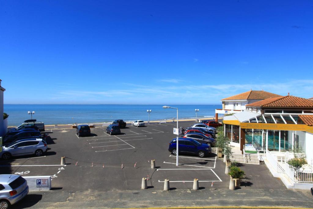 een parkeerplaats naast een strand met de oceaan bij Hotel Les Dunes in La Tranche-sur-Mer