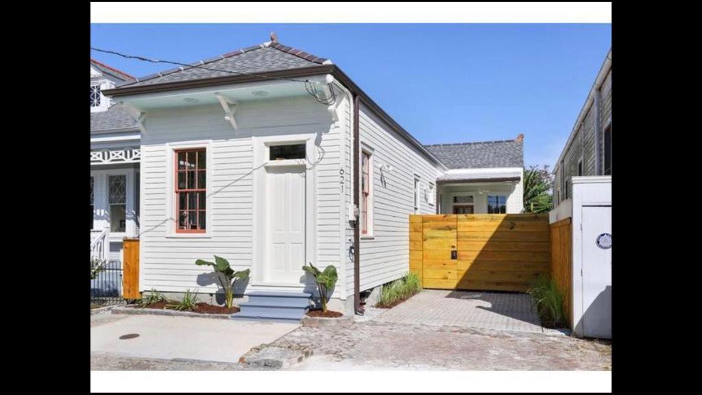 a small white house with a wooden fence at Petite Desire in New Orleans