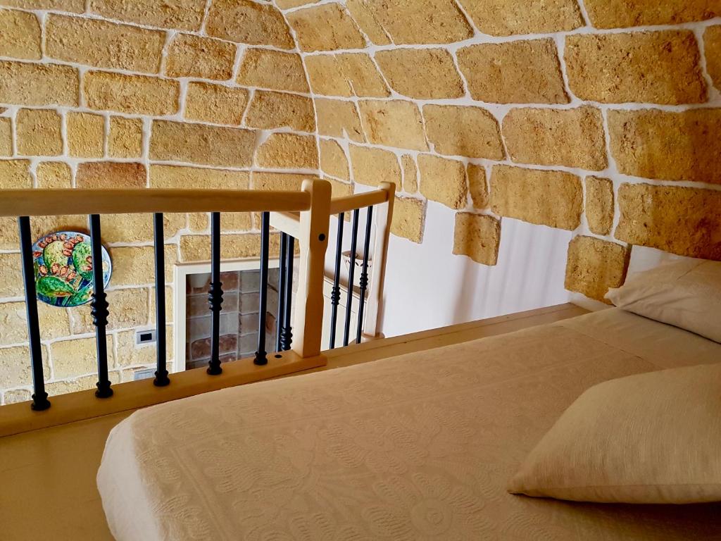 een bed in een kamer met een bakstenen muur bij Dimora La Nicchia in Polignano a Mare