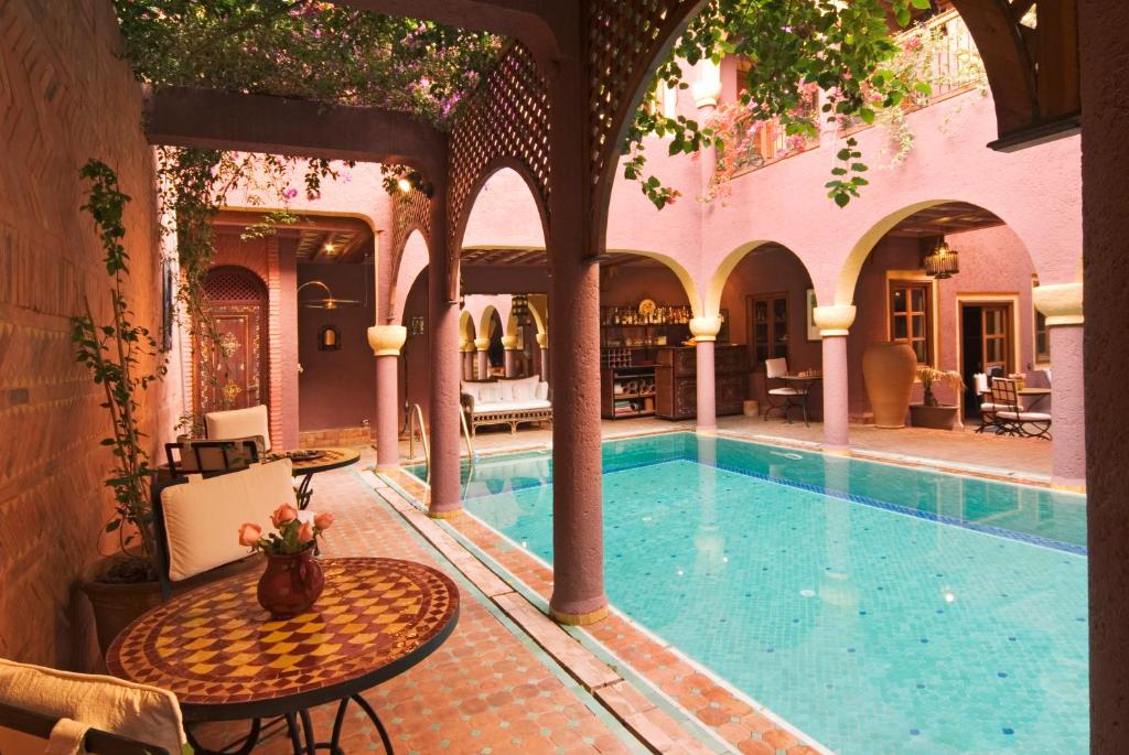 a swimming pool in a building with a table and a table at Riad Noga in Marrakesh