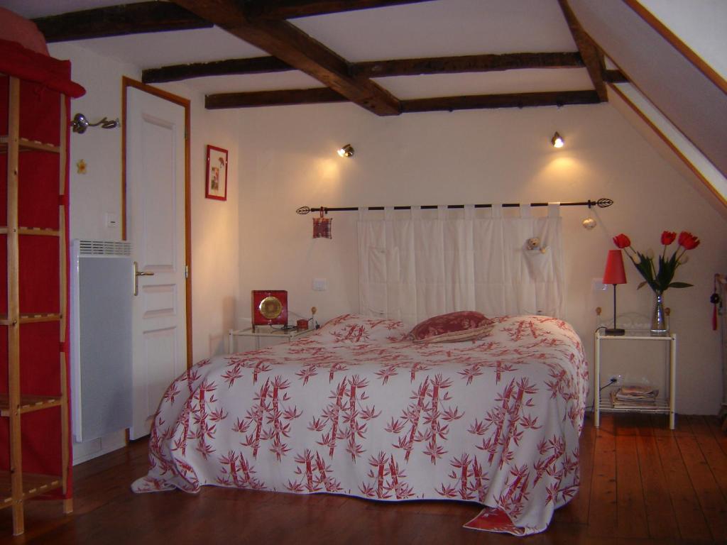 een slaapkamer met een bed met een rode en witte deken bij Le Logis du Roc in Granville