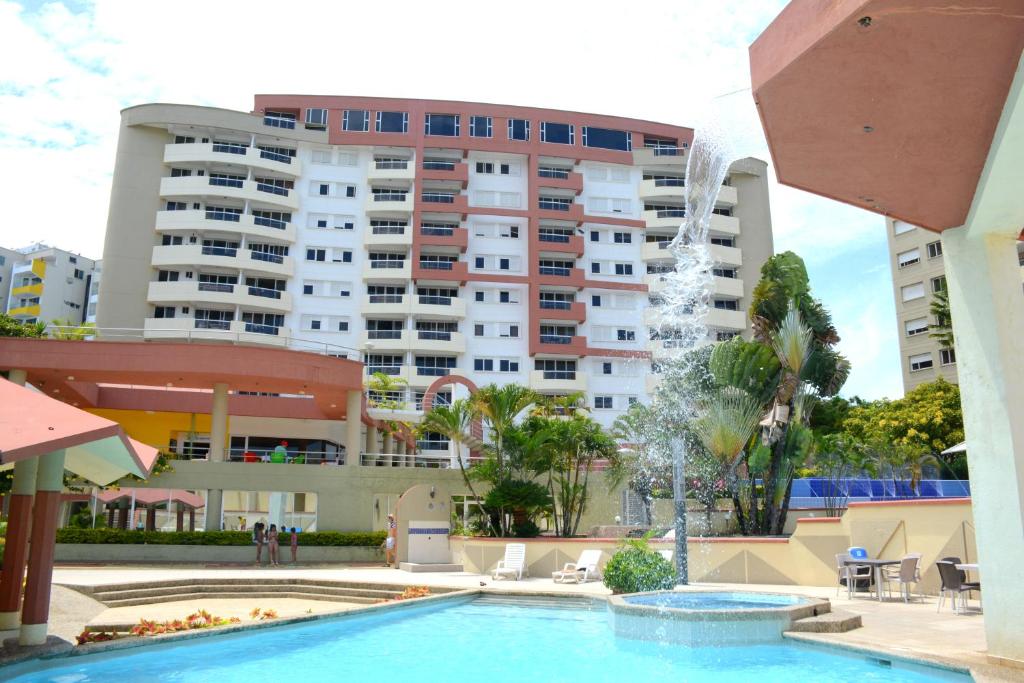 a swimming pool with a fountain in front of a large building at Playa Almendro Resort in Tonsupa