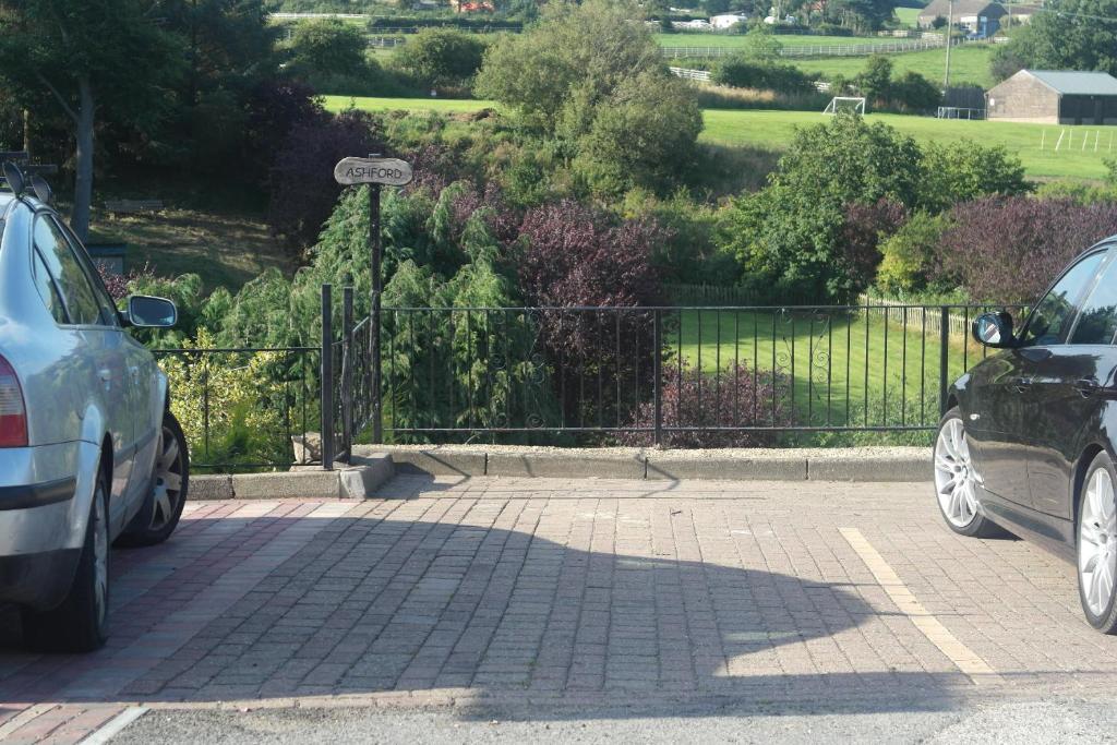two cars parked in a parking lot next to a fence at Ashford house 'The Snug' private hot tub in Fylingthorpe