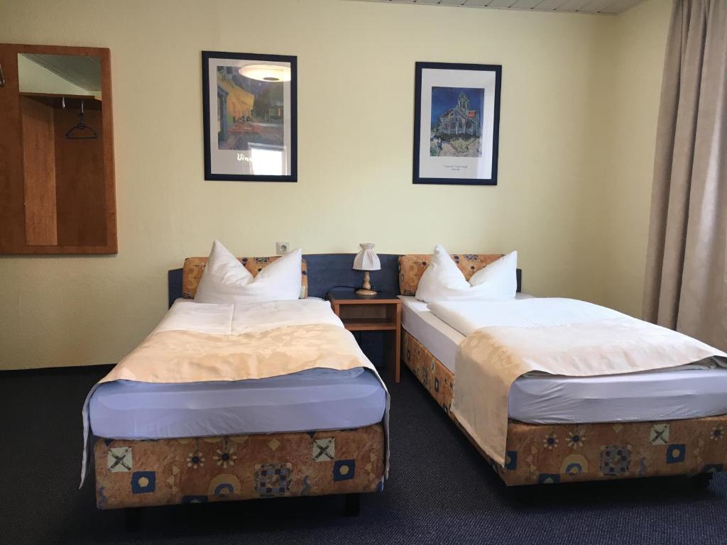 two twin beds in a room with a table at Altes Gasthaus Leuna Pension in Leuna